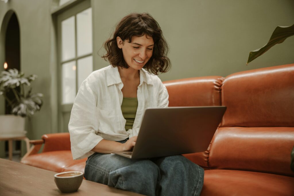 Frau mit braunen Haaren vor einem Laptop auf einer roten Couch symbolisch fuer online Ernaehrungsberatung